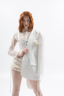 Genç kızıl saçlı bir kadın zarif bir poz veriyor. Parlak bir stüdyoda, bahar modasını gözler önüne seriyor..