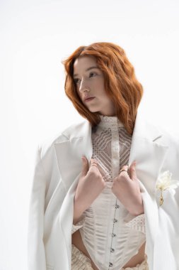 Genç kızıl saçlı bir kadın şık bahar kıyafetini sergiliyor. Stüdyoda zarafet saçıyor..