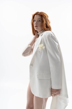 Canlı kızıl saçlı genç bir kadın sanat stüdyosunda modern bahar modasını sergiliyor..