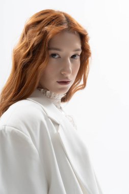 Güzel bir kızıl saçlı zarif bir şekilde bir stüdyoda poz veriyor, zarif bir bahar modası sergiliyor..