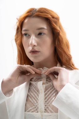 Genç kızıl saçlı bir kadın şık bir stüdyoda poz veriyor, bahar modasının altını çiziyor..