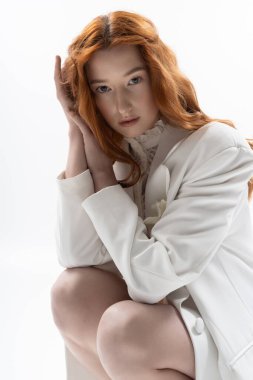 Çarpıcı kızıl saçlı genç bir kadın zarif bir bahar elbisesi içinde zarifçe poz veriyor, zarafeti yakalıyor..