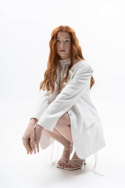 Genç, kızıl saçlı bir kadın zarif bir şekilde poz veriyor. Parlak bir bahar havası var..