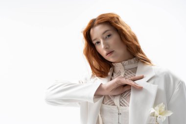 Canlı kızıl saçlı genç bir kadın şık bahar kıyafetleri içinde şık poz veriyor..