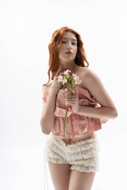 Genç bir kızıl çiçek desenli bir elbiseyle poz verir, bahar modasının özünü yakalar..