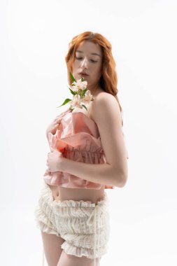 Şık giyinmiş genç bir kadın zarif poz verir baharı somutlaştıran çiçeklerle.