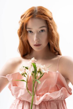 Bahar kıyafetli şık bir kızıl, narin çiçekler taşıyor, gençlik ve cazibe saçıyor..