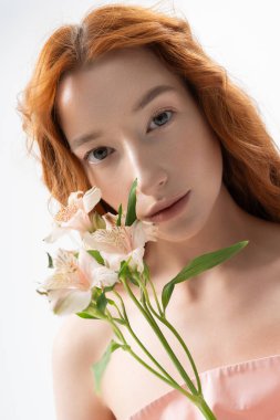 Genç bir kadın tarzını parlak bir stüdyoda çiçeklerle sergiliyor, bahar havası yayıyor..