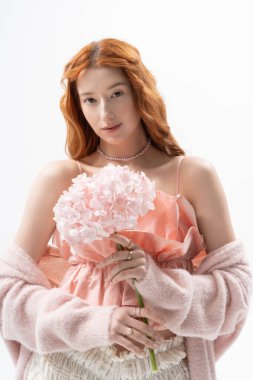 Kızıl saçlı şık bir genç kadın pembe bir çiçek tutuyor, bahar ruhunu yakalıyor..