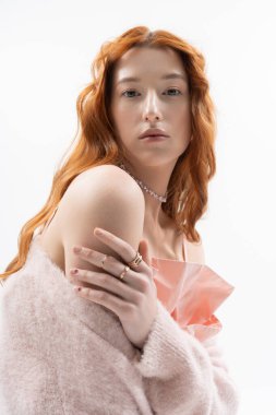 Beyaz stüdyoda bahar atmosferiyle çevrili şık kıyafetli zarif genç bir kadın.