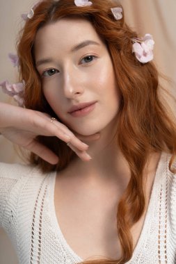 Genç kızıl, canlı bir bahar stüdyosunda çiçeklerle güzel poz veriyor..