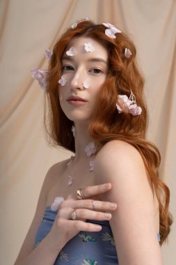 Akan kızıl saçlı genç bir kadın, bahar çiçeklerinin arasında zarifçe poz verir..