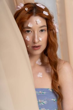 Şık bir kızıl saçlı, çiçek açan, bahar modasını kucaklayan bir stüdyoda poz veriyor..