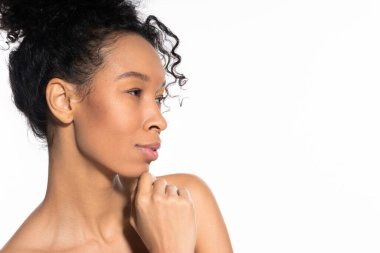 Kıvırcık saçlı genç bir kadın minimalist bir ortamda zarifçe poz verir..