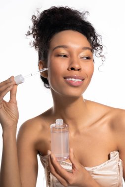 Güzel genç bir kadın serumunu uyguluyor, açık tenini ve neşeli ifadesini sergiliyor..