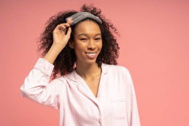 Kıvırcık saçlı güzel bir kadın saç bandı takıyor ve neşe saçarak poz veriyor..