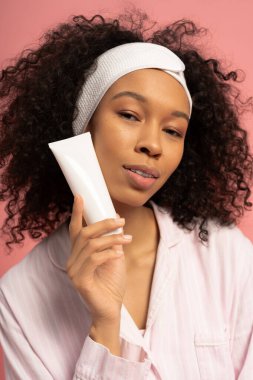 Güzel bir genç kadının zarif bir cilt ürününü tanıttığı parlak bir sahne..