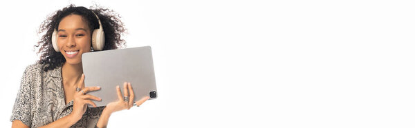 Красивая молодая женщина радостно улыбается, когда она занимается со своим планшетом, слушая музыку.