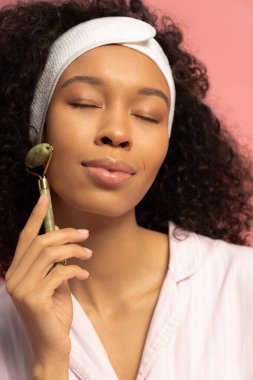Kıvırcık saçlı genç bir kadın yüzüne yeşim bir silindir takmış, huzur ve güzellik saçıyor..