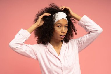 Genç bir kadın, güzellik ayinini canlı pembe bir arka plana karşı sergiliyor..