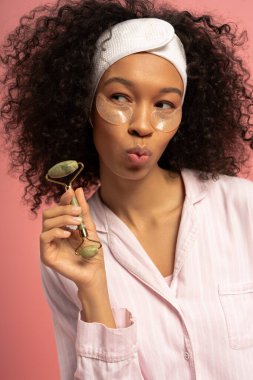 Kıvırcık saçlı şık bir kadın şakacı poz verirken derisini sergiliyor..