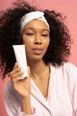 Parlak pembe arka plan, genç bir kadının cilt ürününün tanıtımına duyduğu güveni gösteriyor..