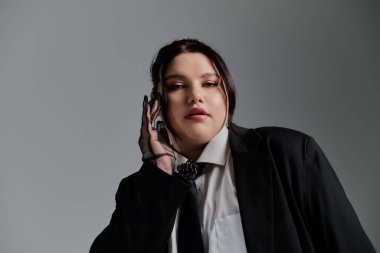 Kendinden emin, iri yarı bir kadın göz kamaştırıcı siyah bir takım elbise içinde, ışıl ışıl bir tarz ve güzellik sergiliyor..