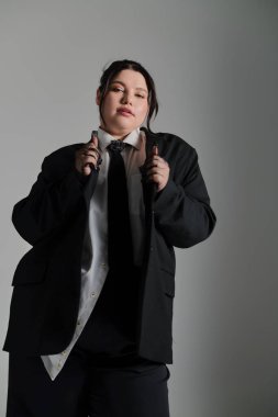 Kendine güveni tam ve cüsseli bir kadın, kendine has moda anlayışını büyük bir takım elbise ve kravatla sergiliyor..