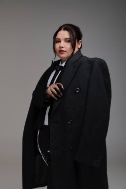 Kendine güveni tam ve cüsseli bir kadın şık bir elbise içinde zarifçe poz verir, zarafet ve stili somutlaştırır..