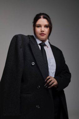 Kendine güveni tam ve cüsseli bir kadın, büyük bir spor ceket ve şık aksesuarlarla cesur bir modaya sahip..