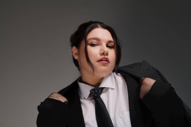 Güzel, kilolu bir kadın, moda anlayışını özel bir takım elbiseyle sergiliyor. Kendine güveni tam..