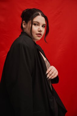 Güzel, iri yarı bir kadın şık bir siyah ceket içinde zarif bir şekilde poz veriyor, eşsiz tarzını sergiliyor..