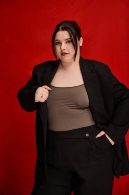 Güzel, iri yarı bir kadın şık, siyah bir elbise içinde rahatça poz verir, ışık saçar ve dengede durur..