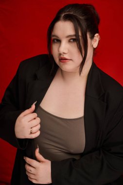 Güzel, iri yarı bir kadın şık bir kıyafet içinde, kendine güven ve tarz yayarak zarifçe poz verir..