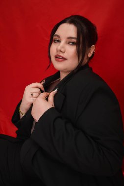 Şık giyinmiş güzel, iri yarı bir kadın zarif pozlar veriyor, kendine güveni ve tarzı var..