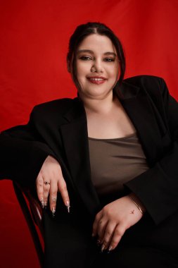 Kendinden emin ve iri bir kadın zarifçe otururken cazibe ve tarz yayar..