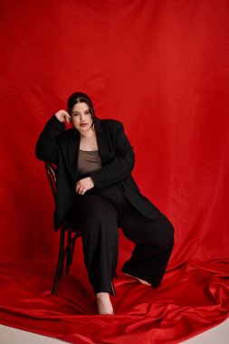 Şık ve iri yarı bir kadın zarif bir şekilde sandalyeye oturur ve kendine güvenir..