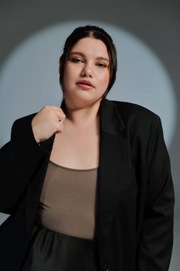 Güzel, iri yarı bir kadın moda anlayışını şık bir kıyafetle sergiliyor. Kendine güveni tam..