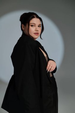 Güzel ve büyük bir kadın modaya uygun bir moda sergilerken, minimalist bir ortama güven yayıyor..