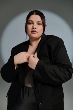 Göz kamaştırıcı, iri yarı bir kadın, kendine güveni tam, şık siyah bir ceketle tarzını sergiliyor..