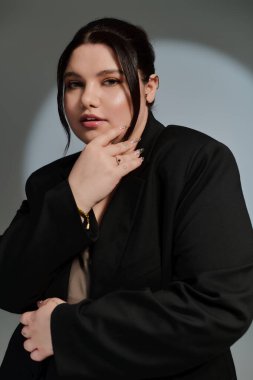 Kendine güvenen, iri yarı bir kadın zarif bir şekilde poz verir..