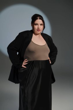 Güzel, büyük beden bir kadın zarif bir elbise ve ceket giyerek moda anlayışını sergiliyor..