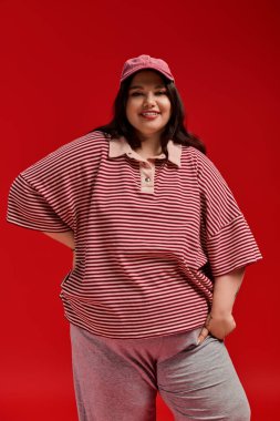 Kendine güvenen bir kadın moda anlayışını canlı kırmızı çizgili üst ve şapkasıyla sergiliyor..