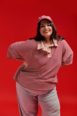 Kendine güvenen, iri yarı bir kadın eşsiz tarzını ifade eder. Çekici bir gülümsemeyle gururla durur..