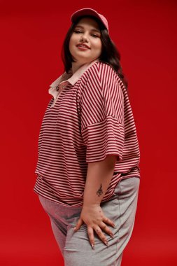 Artı cüsseli bir kadın zarif bir şekilde çizgili bir kıyafet içinde, benzersiz moda anlayışını sergiliyor..