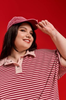 Büyük bedenli bir kadın, parlak bir gülümsemeyle kırmızı bir arka plana karşı modasını sergiliyor..