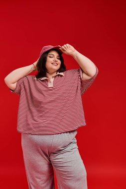 Büyük beden bir kadın moda anlayışını sergiliyor. Gülümsüyor ve komik bir şekilde poz veriyor..