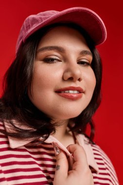 Parlak kırmızı arka plan şık giyinmiş, iri yarı bir kadının çekiciliğini ön plana çıkarıyor..