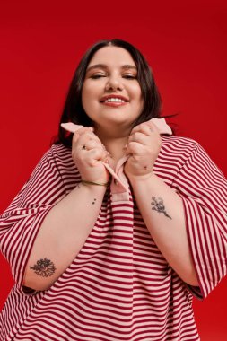 Büyük beden bir kadın, neşeli bir gülümseme ve kendine güvenen bir pozla modasını sergiliyor..