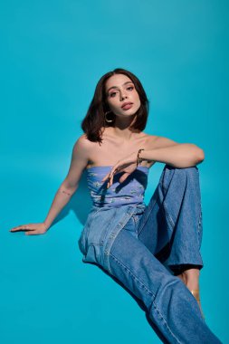 Genç bir kadın canlı mavi bir duvara karşı şık poz verir..